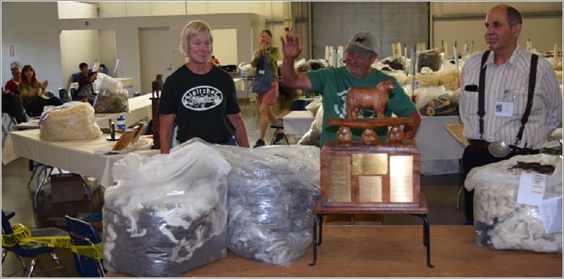 John Steitzhof waves to the audience to thank them for their applause as he and his wife, Carol, were awarded the BSN Cup for the five Most Valuable Handspinning Fleeces from a Single Producer by Judge David Cook. Photo: Rich Lundquist.